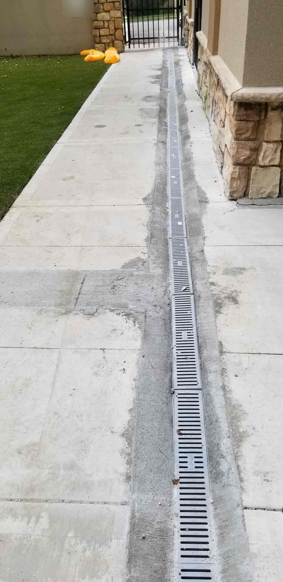 Channel drain set in a concrete walk along a building