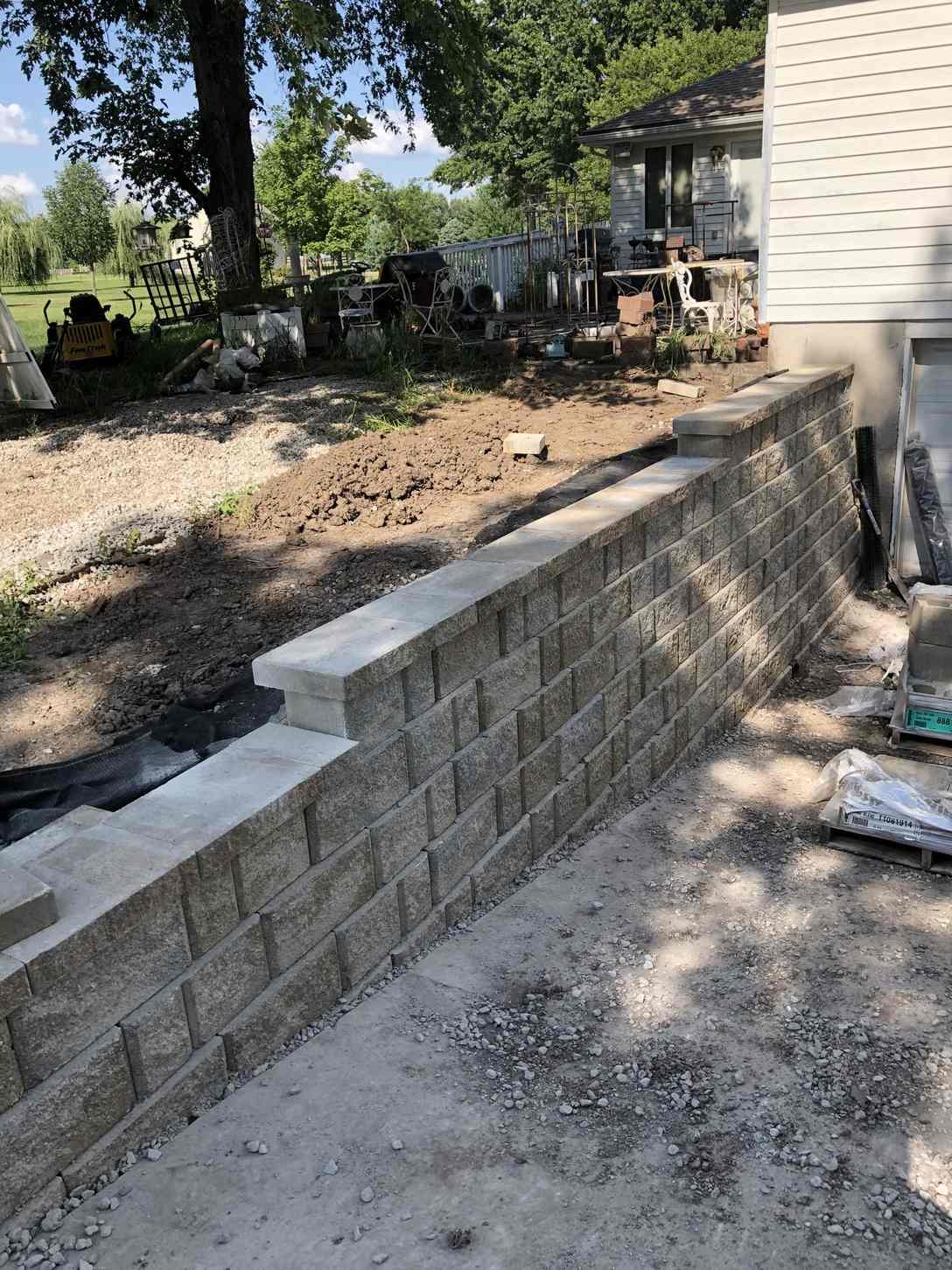 Capped block retaining wall running along a house