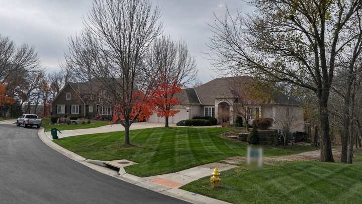 Cleared corner-lot lawn along a curving residential street in fall